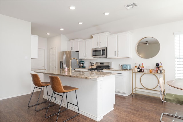 kitchen with a breakfast bar area, white cabinetry, a kitchen island with sink, and appliances with stainless steel finishes