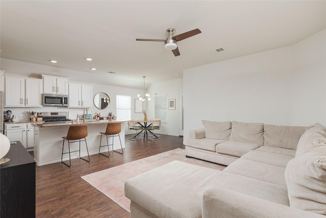 living room featuring dark hardwood / wood-style flooring and ceiling fan with notable chandelier