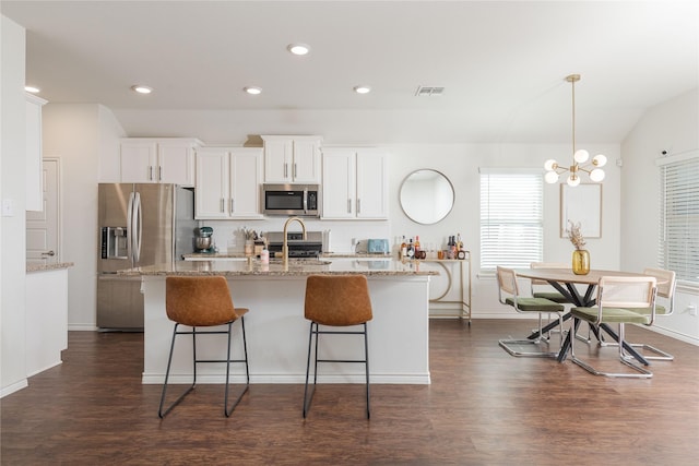 kitchen featuring appliances with stainless steel finishes, white cabinets, and a center island with sink