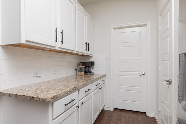 kitchen with white cabinets, decorative backsplash, light stone counters, and dark wood-type flooring