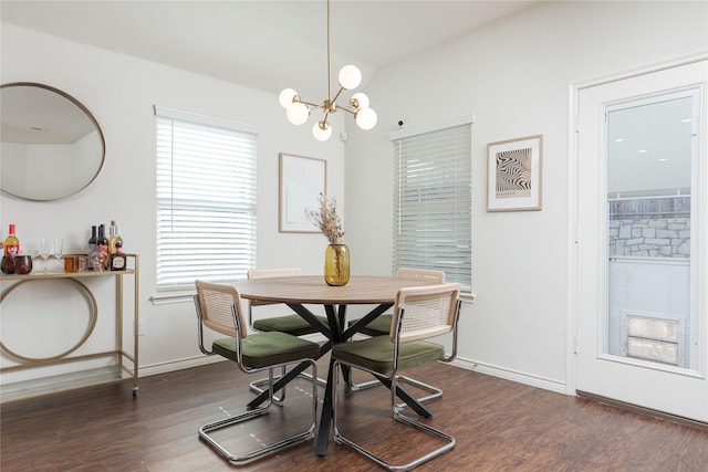 dining space featuring dark wood-type flooring and an inviting chandelier