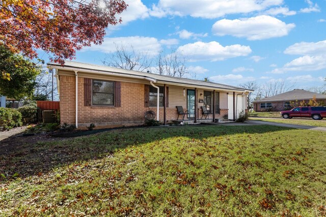 single story home featuring a front yard, a porch, central AC, and a garage