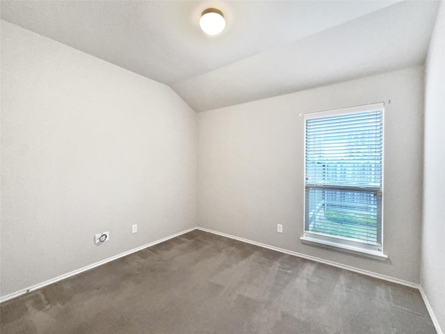 carpeted empty room with vaulted ceiling