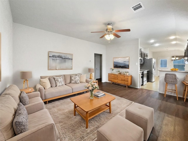 living room featuring dark hardwood / wood-style flooring and ceiling fan with notable chandelier