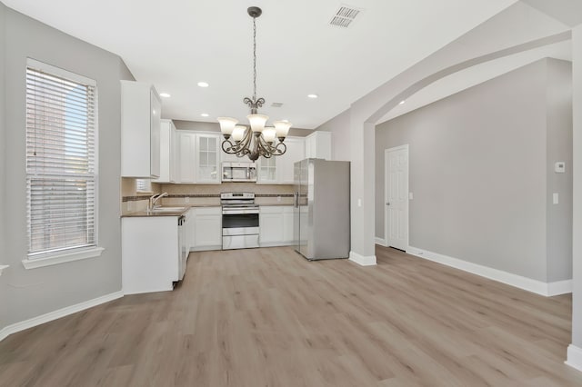 kitchen featuring appliances with stainless steel finishes, pendant lighting, tasteful backsplash, white cabinetry, and sink