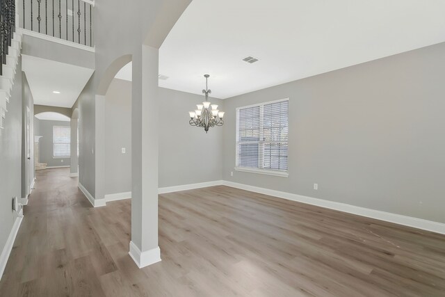 unfurnished room featuring light wood-type flooring and an inviting chandelier