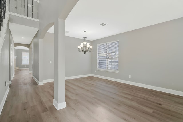 empty room with light hardwood / wood-style flooring and a chandelier