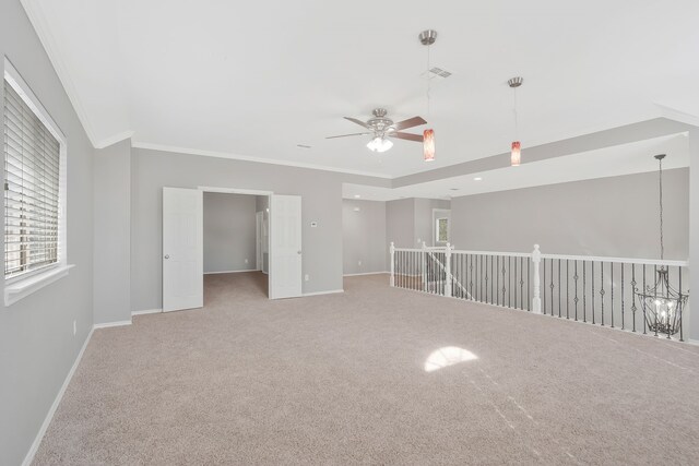 carpeted spare room featuring ceiling fan with notable chandelier and ornamental molding