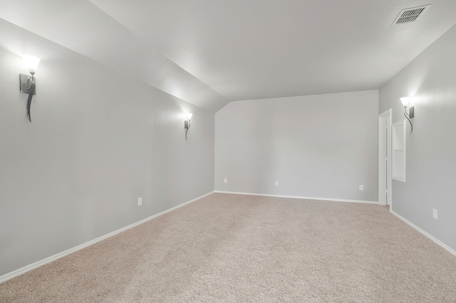 spare room featuring light carpet and lofted ceiling