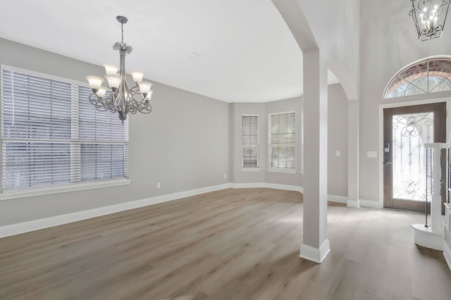 foyer entrance with a healthy amount of sunlight, an inviting chandelier, and light hardwood / wood-style floors