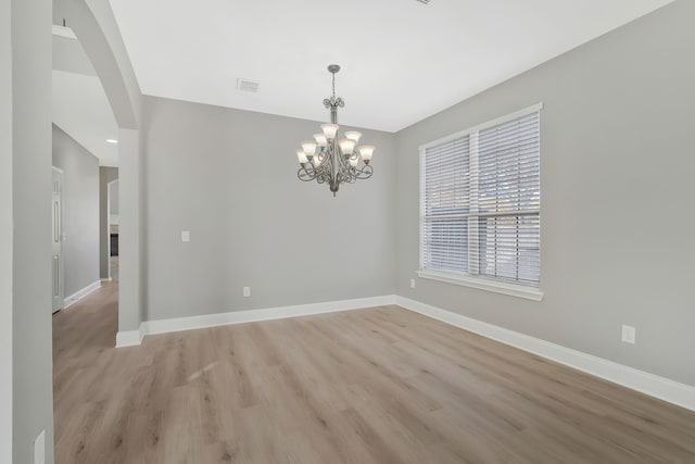 unfurnished room featuring light hardwood / wood-style flooring and a chandelier