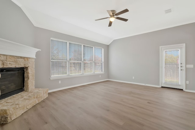 unfurnished living room featuring a stone fireplace, lofted ceiling, ornamental molding, ceiling fan, and light wood-type flooring