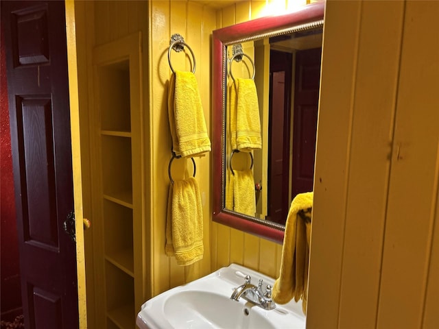 bathroom with wooden walls and a sink