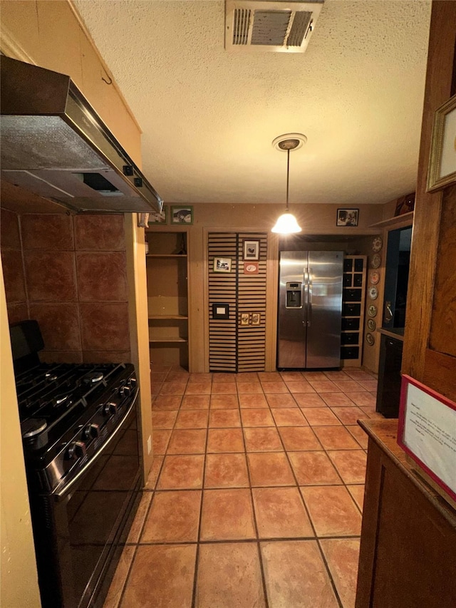 1828 Shepheard St, Fort Worth, TX 76114 - kitchen featuring stainless steel fridge with ice dispenser, range with gas cooktop, under cabinet range hood, a textured ceiling, and light tile patterned flooring