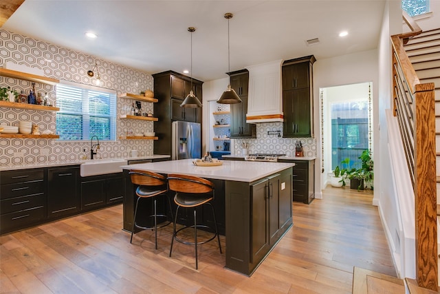 kitchen featuring a center island, sink, appliances with stainless steel finishes, and light hardwood / wood-style flooring