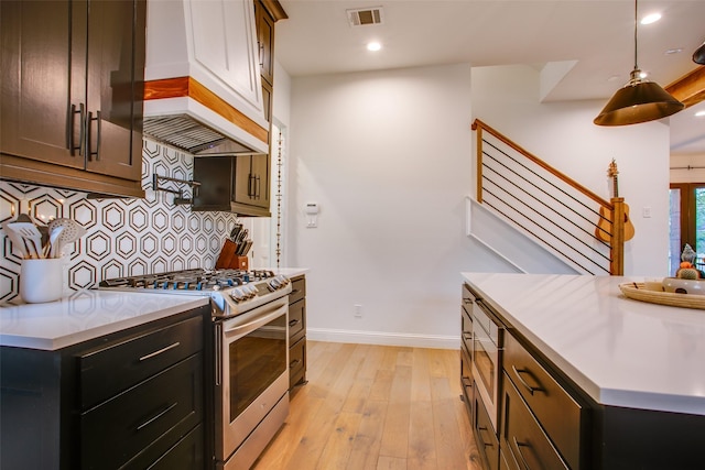 kitchen featuring tasteful backsplash, stainless steel gas stove, decorative light fixtures, and light hardwood / wood-style flooring