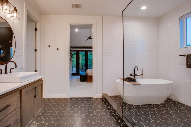 bathroom featuring vanity, tile patterned floors, tile walls, and a tub