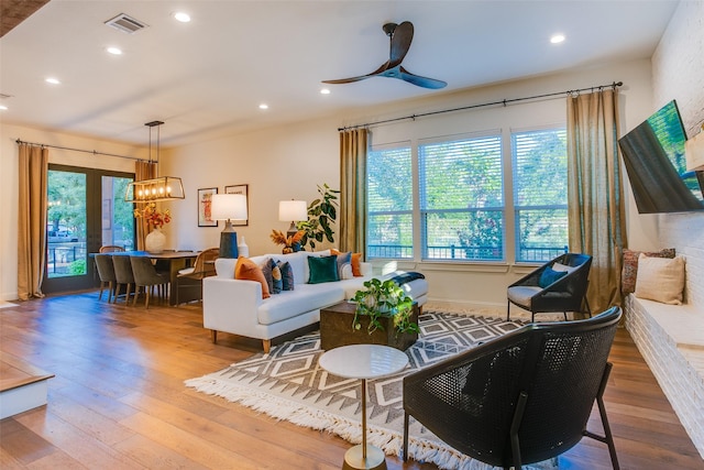 living room with ceiling fan with notable chandelier and wood-type flooring