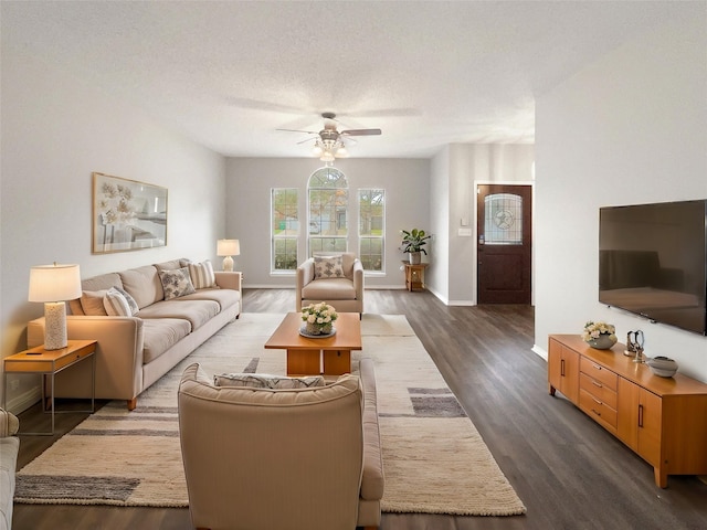 living room featuring a textured ceiling, ceiling fan, and dark wood-type flooring