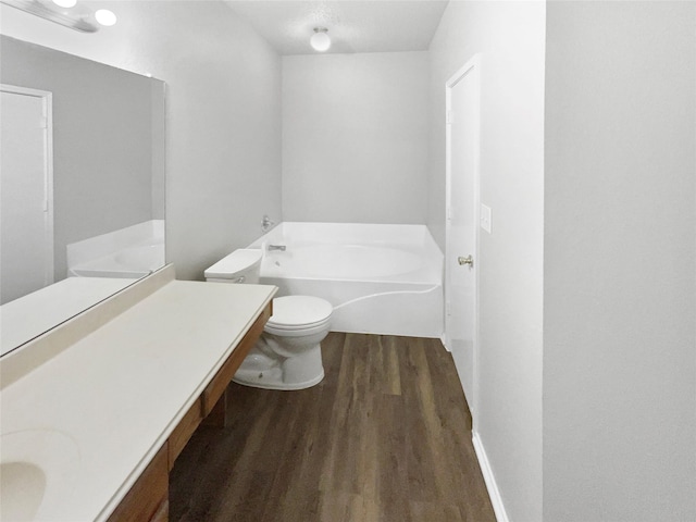 bathroom featuring a washtub, hardwood / wood-style floors, vanity, and toilet