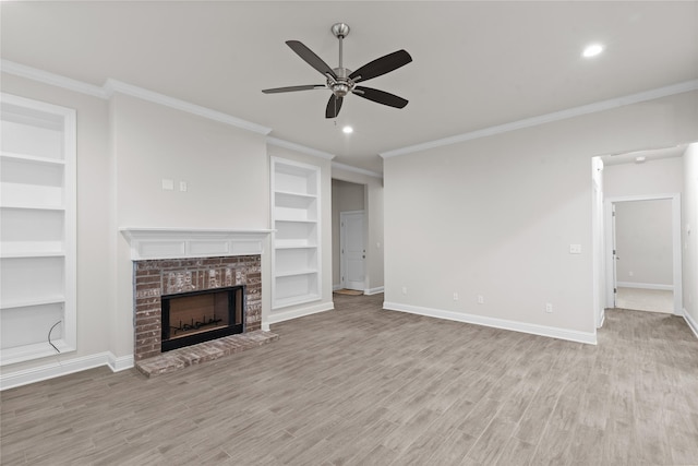 unfurnished living room with ceiling fan, a brick fireplace, built in features, crown molding, and light hardwood / wood-style floors