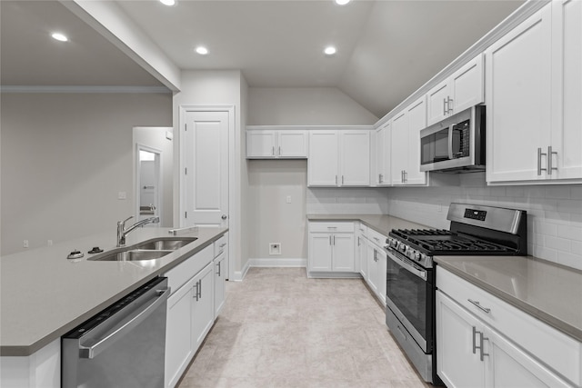 kitchen featuring backsplash, white cabinets, sink, vaulted ceiling, and appliances with stainless steel finishes