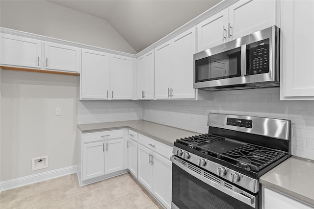 kitchen featuring backsplash, stainless steel appliances, light tile patterned floors, white cabinets, and lofted ceiling