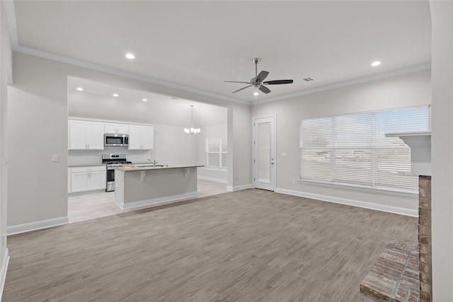 kitchen with hanging light fixtures, stainless steel appliances, white cabinets, ceiling fan with notable chandelier, and light wood-type flooring