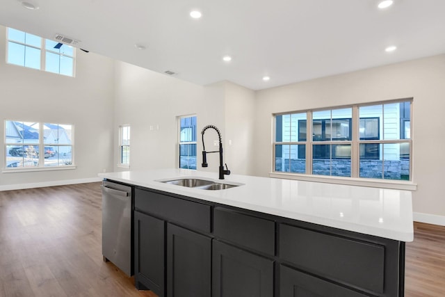 kitchen featuring sink, light wood-type flooring, dishwasher, and a center island with sink