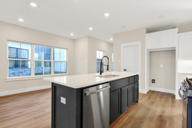 kitchen with sink, stainless steel appliances, light hardwood / wood-style floors, and a center island with sink