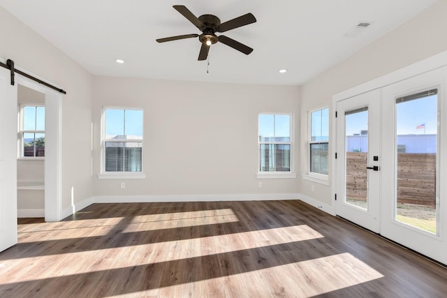 spare room with dark wood-type flooring, ceiling fan, a barn door, and french doors