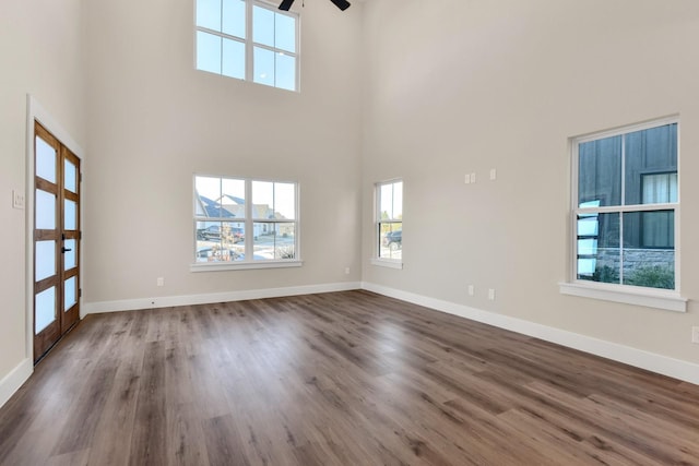 interior space featuring dark wood-type flooring, ceiling fan, and a towering ceiling