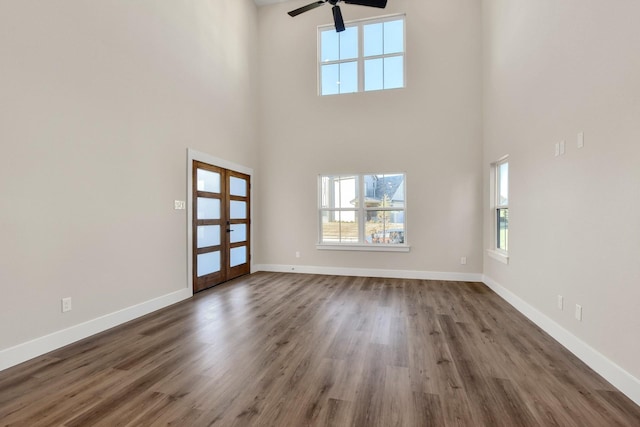 foyer with dark wood-type flooring, ceiling fan, french doors, and a towering ceiling