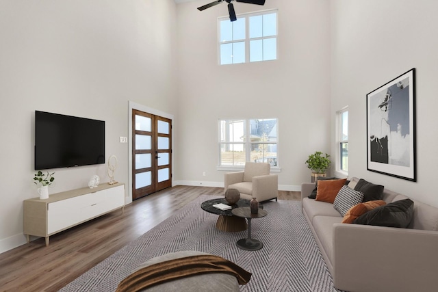 living room with dark hardwood / wood-style flooring, a towering ceiling, french doors, and ceiling fan