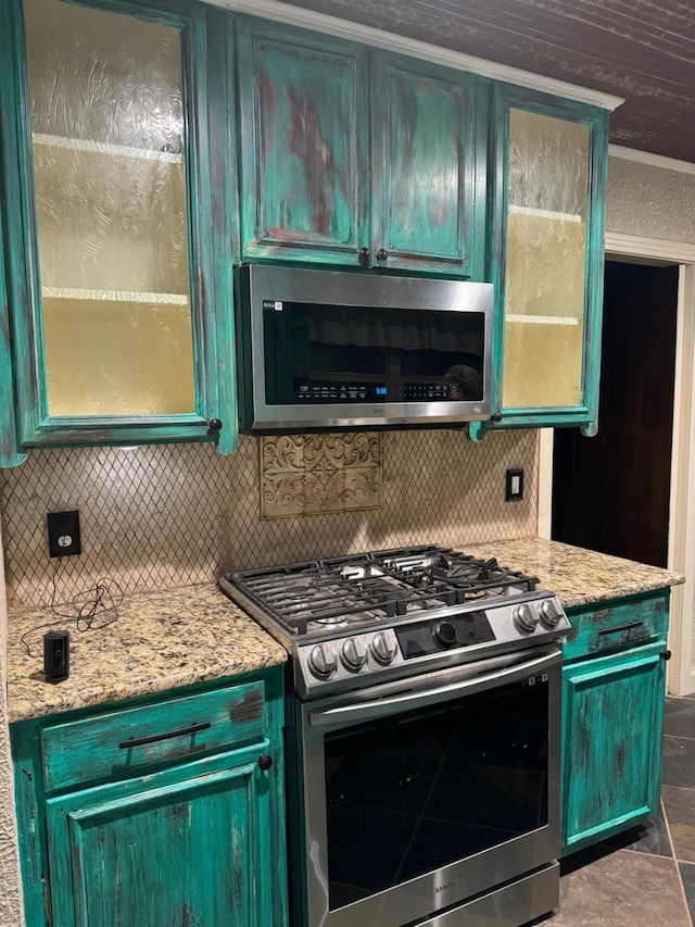 kitchen featuring decorative backsplash, light stone counters, ornamental molding, and stainless steel appliances