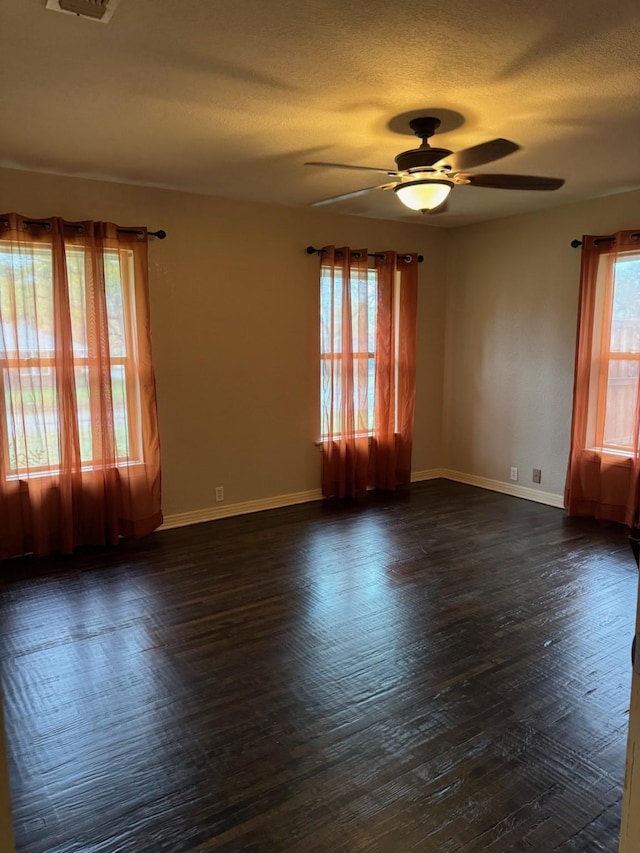 unfurnished room featuring ceiling fan, a healthy amount of sunlight, and dark hardwood / wood-style floors