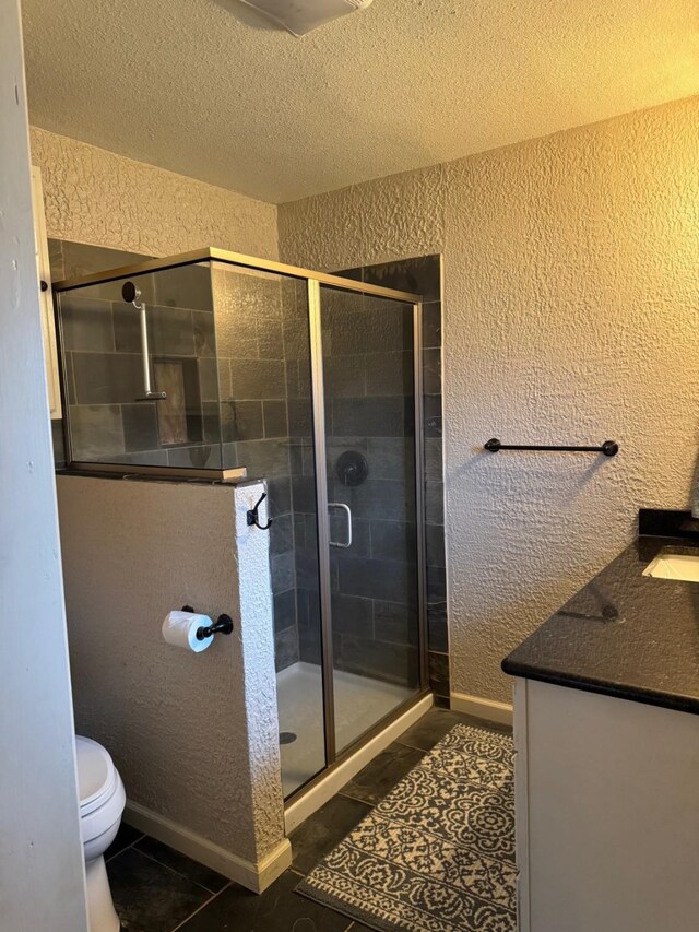 bathroom with vanity, tile patterned floors, toilet, a textured ceiling, and an enclosed shower