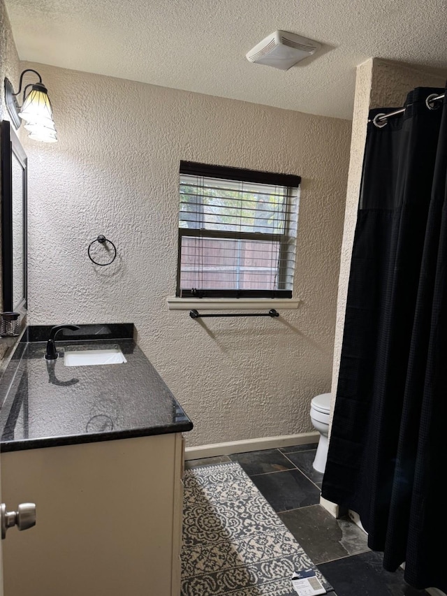 bathroom with a textured ceiling, vanity, and toilet