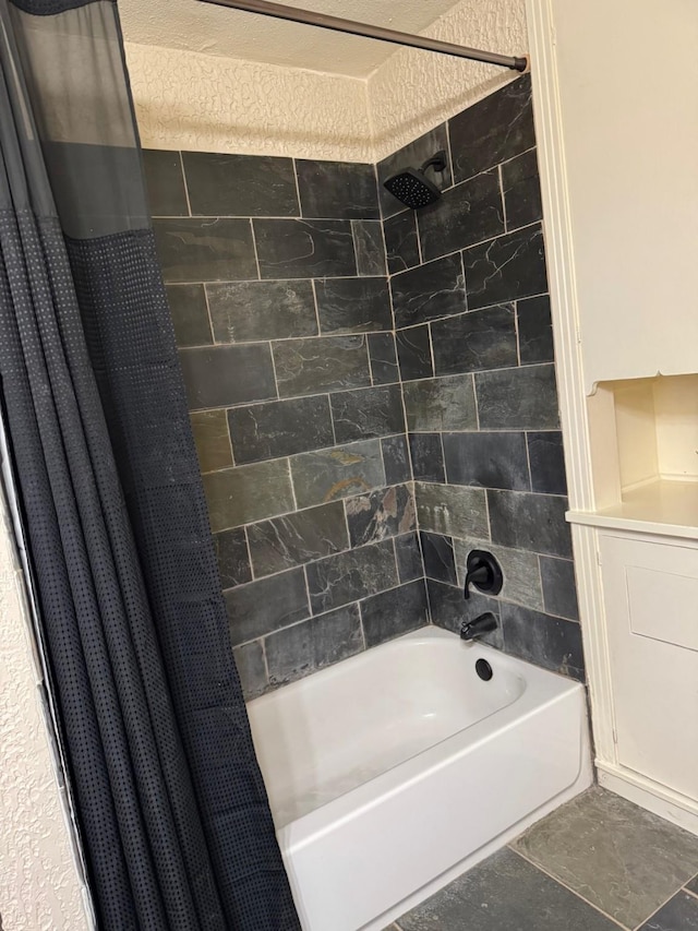 bathroom with a textured ceiling and shower / tub combo