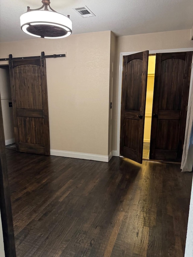 entrance foyer with a textured ceiling, a barn door, and dark wood-type flooring