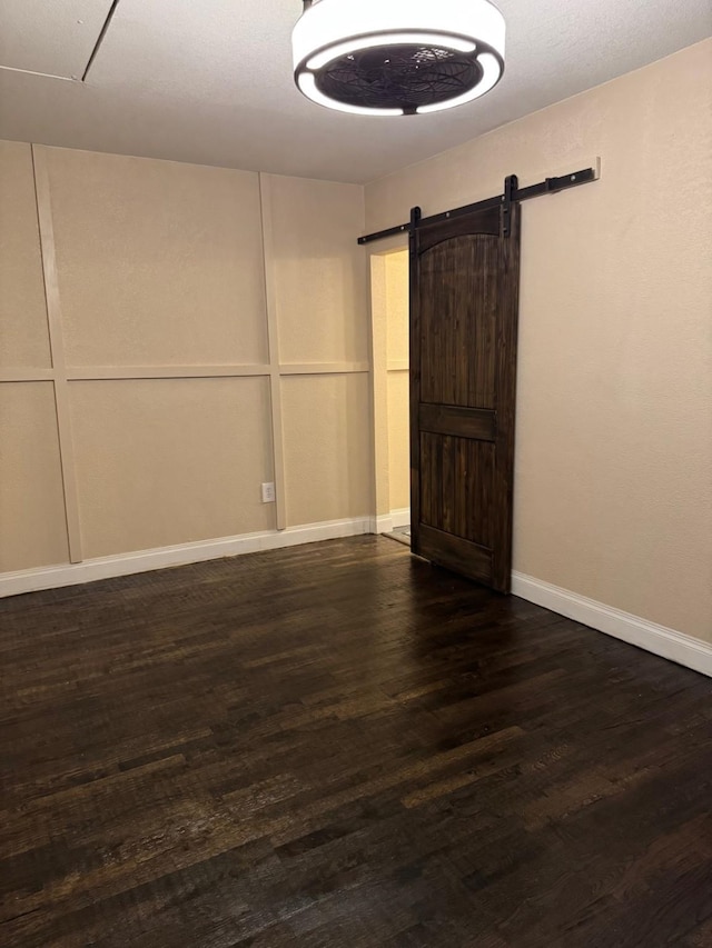 empty room with dark hardwood / wood-style floors and a barn door