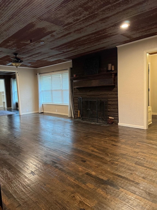 unfurnished living room with a large fireplace, ceiling fan, dark wood-type flooring, and wood ceiling