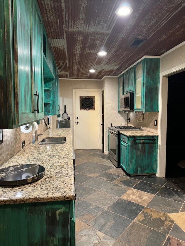 kitchen with sink, stainless steel appliances, light stone counters, green cabinetry, and ornamental molding