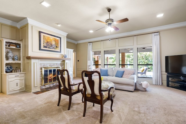 living room with ceiling fan, light colored carpet, ornamental molding, and a tile fireplace