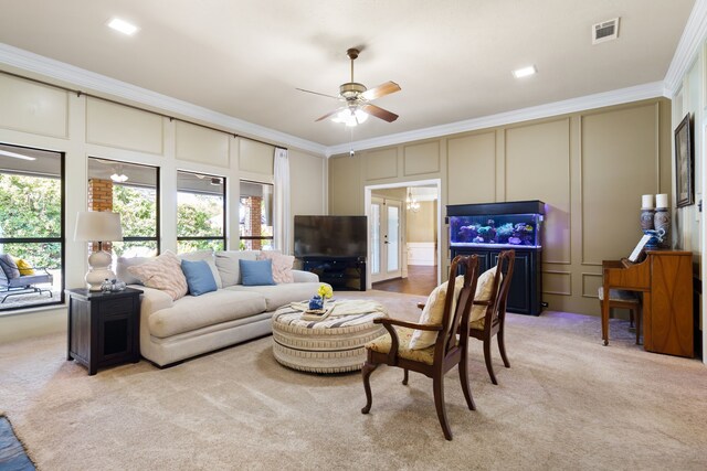 carpeted living room with ceiling fan and ornamental molding