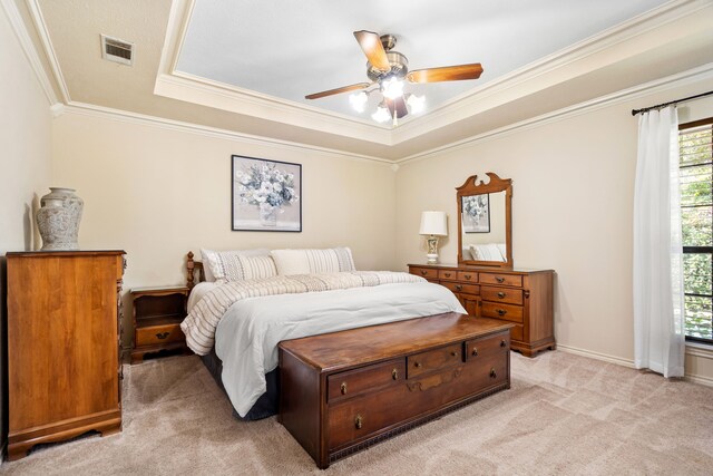 carpeted bedroom with ceiling fan, ornamental molding, and a tray ceiling