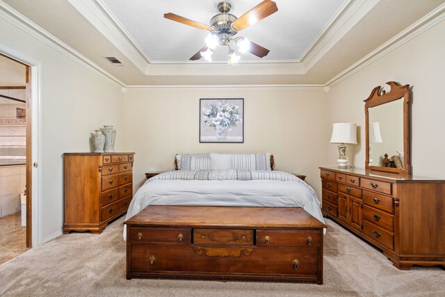 carpeted bedroom with a raised ceiling, ensuite bath, ceiling fan, and crown molding