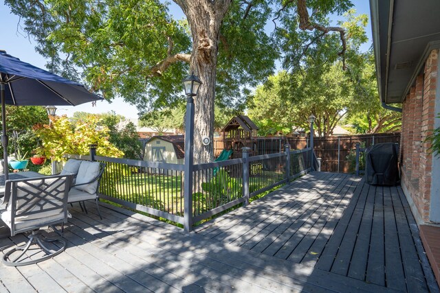 deck with a playground and a storage unit