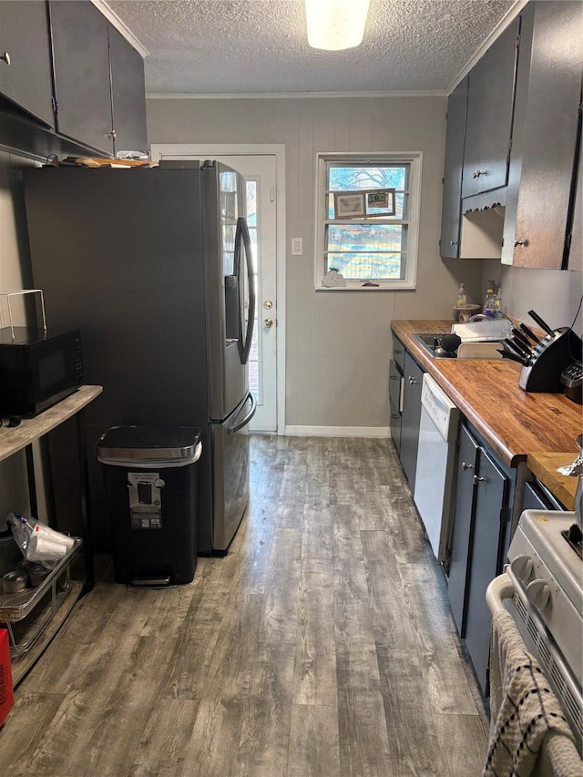 kitchen featuring butcher block countertops, white appliances, crown molding, a textured ceiling, and light hardwood / wood-style flooring