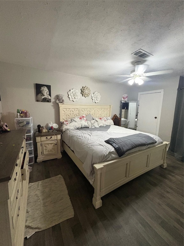 bedroom featuring ceiling fan, dark hardwood / wood-style flooring, and a textured ceiling